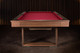 Wide lifestyle shot of the Doc & Holliday Billiards Santorini Slate Pool Table in walnut positioned in a luxury interior with dark reeded walls and soft atmospheric light Wide lifestyle shot of the Doc & Holliday Billiards Santorini Slate Pool Table in walnut positioned in a luxury interior with dark reeded walls and soft atmospheric light